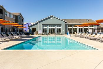 A large swimming pool in front of a building with orange umbrellas.